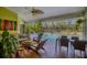 Open sunroom with tropical views to screened-in pool, dining area, lounge area and ceiling fan at 850 Van Gogh Road, Englewood, FL 34223