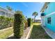 A charming side yard with well-manicured hedges leading to the home's blue exterior at 9230 Pine Cove Dr, Englewood, FL 34224