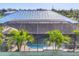 Aerial view of a beautiful pool and screened-in patio surrounded by lush tropical landscaping and a blue metal roof at 10039 Sunday Dr, Port Charlotte, FL 33981