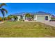 Charming single-story home featuring a well-manicured lawn, vibrant green exterior, and a striking blue metal roof at 10039 Sunday Dr, Port Charlotte, FL 33981