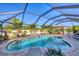 Inviting screened-in pool area surrounded by lush landscaping, brick pavers, lounge chairs, and an umbrella-covered dining table at 10039 Sunday Dr, Port Charlotte, FL 33981