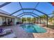 Beautiful screened-in pool with a lush tropical backdrop and a brick-paved patio with comfortable lounge chairs at 10039 Sunday Dr, Port Charlotte, FL 33981