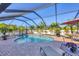 Inviting screened-in pool area surrounded by lush landscaping, brick pavers, lounge chairs, and an umbrella-covered dining table at 10039 Sunday Dr, Port Charlotte, FL 33981