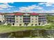 Aerial view of building exterior and pond with red roofs, tan siding, and screened balconies at 10055 Links Ln # 402, Rotonda West, FL 33947