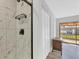 Modern shower with white marble-look tile, dark fixtures, and open access to the main bedroom at 11 Quails Run Blvd # 9, Englewood, FL 34223