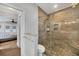 Modern bathroom with a glass-enclosed shower, stone floor and a wooden accent wall at 11101 Sandrift Ave, Englewood, FL 34224