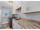 Well-lit laundry room with sink, counter space, cabinets, and modern appliances at 11101 Sandrift Ave, Englewood, FL 34224