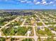Wide neighborhood aerial shot showing the layout with blue skies and green landscaping at 115 Australian Dr, Rotonda West, FL 33947