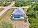 Overhead view of a home with a screened-in pool surrounded by lush greenery and neighborhood streets at 115 Australian Dr, Rotonda West, FL 33947