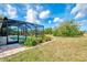 View of the backyard with screen enclosed lanai and pool, and partial landscaping at 115 Australian Dr, Rotonda West, FL 33947