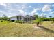 Backyard view of home featuring a screened lanai, pool, and partial landscaping at 115 Australian Dr, Rotonda West, FL 33947