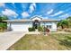Charming home featuring a manicured lawn, mature landscaping, and an attached two-car garage at 115 Australian Dr, Rotonda West, FL 33947