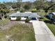 An elevated view showcasing a well-maintained white house, spacious driveway, and landscaped front yard at 1493 Kathleen Pl, Englewood, FL 34223
