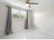 Cozy bedroom with a ceiling fan, a window and gray curtains at 1493 Kathleen Pl, Englewood, FL 34223