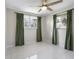 Bright bedroom featuring tile floors, ceiling fan, and two windows with green curtains at 1493 Kathleen Pl, Englewood, FL 34223