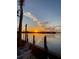 Sunset view over the water with dock pilings and chairs in the foreground at 1493 Kathleen Pl, Englewood, FL 34223