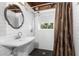 Bathroom with wood ceiling beam, white subway tile, pedestal sink, shower with brown curtain and black floor at 1530 Philip Pl, Englewood, FL 34223
