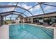 Relax in the beautiful screened pool with ample seating, BBQ, and tv for the ultimate in backyard entertainment at 18 Annapolis Ln, Rotonda West, FL 33947