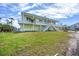 Bright yellow two-story home featuring a charming white staircase, balcony, and tropical landscaping at 1905 Mississippi Ave, Englewood, FL 34224