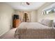 This bedroom includes a ceiling fan, dresser with a TV, window, and a set of doors that lead to a balcony at 2020 E Dolphin Dr, Englewood, FL 34223