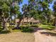 An inviting home features a long driveway, manicured lawns, and beautiful trees creating a secluded setting at 2020 E Dolphin Dr, Englewood, FL 34223
