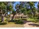 Charming yellow home surrounded by lush trees and landscaping, evoking a serene and inviting atmosphere at 2020 E Dolphin Dr, Englewood, FL 34223