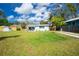 Expansive backyard featuring a well-maintained lawn, shed, driveway, and lovely white house with a light blue accent awning at 221 Nippino E Trl, Nokomis, FL 34275