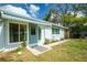 Inviting home front entrance with awning, blue door and trim, surrounded by lush landscaping and a clear walkway at 221 Nippino E Trl, Nokomis, FL 34275