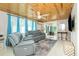 Cozy living room featuring comfortable gray seating, wood paneling, modern ceiling fan, and elegant tiled flooring at 221 Nippino E Trl, Nokomis, FL 34275