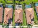 Aerial view showcasing the tile roofs and screened-in pools of three well-manicured homes at 24181 Gallberry Dr, Venice, FL 34293
