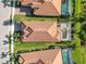 Aerial view of three homes with tile roofs and screened-in pools, set in lush green lawns at 24181 Gallberry Dr, Venice, FL 34293