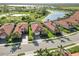 An aerial view captures a community of homes, showcasing their tile roofs and landscaping near a picturesque lake at 24181 Gallberry Dr, Venice, FL 34293