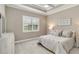 Cozy bedroom featuring a tray ceiling, a ceiling fan, a neutral color palette, and a window with natural light at 24181 Gallberry Dr, Venice, FL 34293