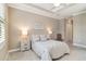 Neutral bedroom boasts a tray ceiling, soft carpet, and a comfortable bed with bedside tables and lamps at 24181 Gallberry Dr, Venice, FL 34293