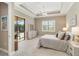 Sunlit bedroom with patio access, tray ceiling, a neutral palette, and natural light streaming in through the windows at 24181 Gallberry Dr, Venice, FL 34293
