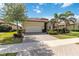 Exterior shot of home with a two-car garage, complemented by lush landscaping and brick paver driveway at 24181 Gallberry Dr, Venice, FL 34293