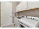 Functional laundry room with white cabinetry, a sink, a full sized washer and dryer, and a control panel at 24181 Gallberry Dr, Venice, FL 34293
