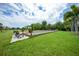 Lush green lawn featuring a bocce ball court, benches, and mature shade trees at 25188 Marion Ave # D308, Punta Gorda, FL 33950