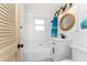 Clean and modern bathroom with a shower-tub combo, white vanity, and nautical-themed accents at 350 W Cowles St, Englewood, FL 34223