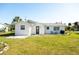 The back of the home features a simple design with outdoor seating and a grill on a green lawn at 350 W Cowles St, Englewood, FL 34223