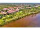 Aerial view of waterfront community with condos featuring red tile roofs, lush landscaping, and waterfront views at 4692 Club Dr # 101, Port Charlotte, FL 33953