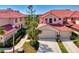 Beautiful building exterior with lush landscaping, barrel tile roof, and paver driveway leading to a two-car garage at 4692 Club Dr # 101, Port Charlotte, FL 33953