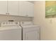 A bright laundry room featuring a white washer and dryer with white cabinets at 4692 Club Dr # 101, Port Charlotte, FL 33953