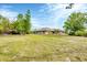 Green backyard, mature trees and the back of a single-story home with screened lanai at 533 Boundary Blvd, Rotonda West, FL 33947