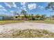 Quaint home with a well-kept lawn and mature trees under a bright blue sky with scattered clouds at 551 Morrison Ave, Englewood, FL 34223
