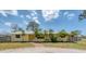Charming yellow home featuring a brick walkway and beautifully landscaped front yard with mature palm trees at 551 Morrison Ave, Englewood, FL 34223