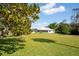 Large grassy backyard with mature landscaping and screened lanai, offering privacy and space for outdoor activities at 60 N Oxford Dr, Englewood, FL 34223