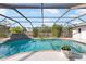 Sparkling pool features waterfall features and is surrounded by a screened-in enclosure with views of the yard at 60 N Oxford Dr, Englewood, FL 34223