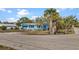 The exterior view captures the light blue home with palm trees, landscaping, and a sandy yard at 7035 Duke St, Englewood, FL 34224