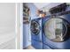 The laundry room features a modern blue washer and dryer set with shelving for storage and a white shutter door at 7035 Duke St, Englewood, FL 34224